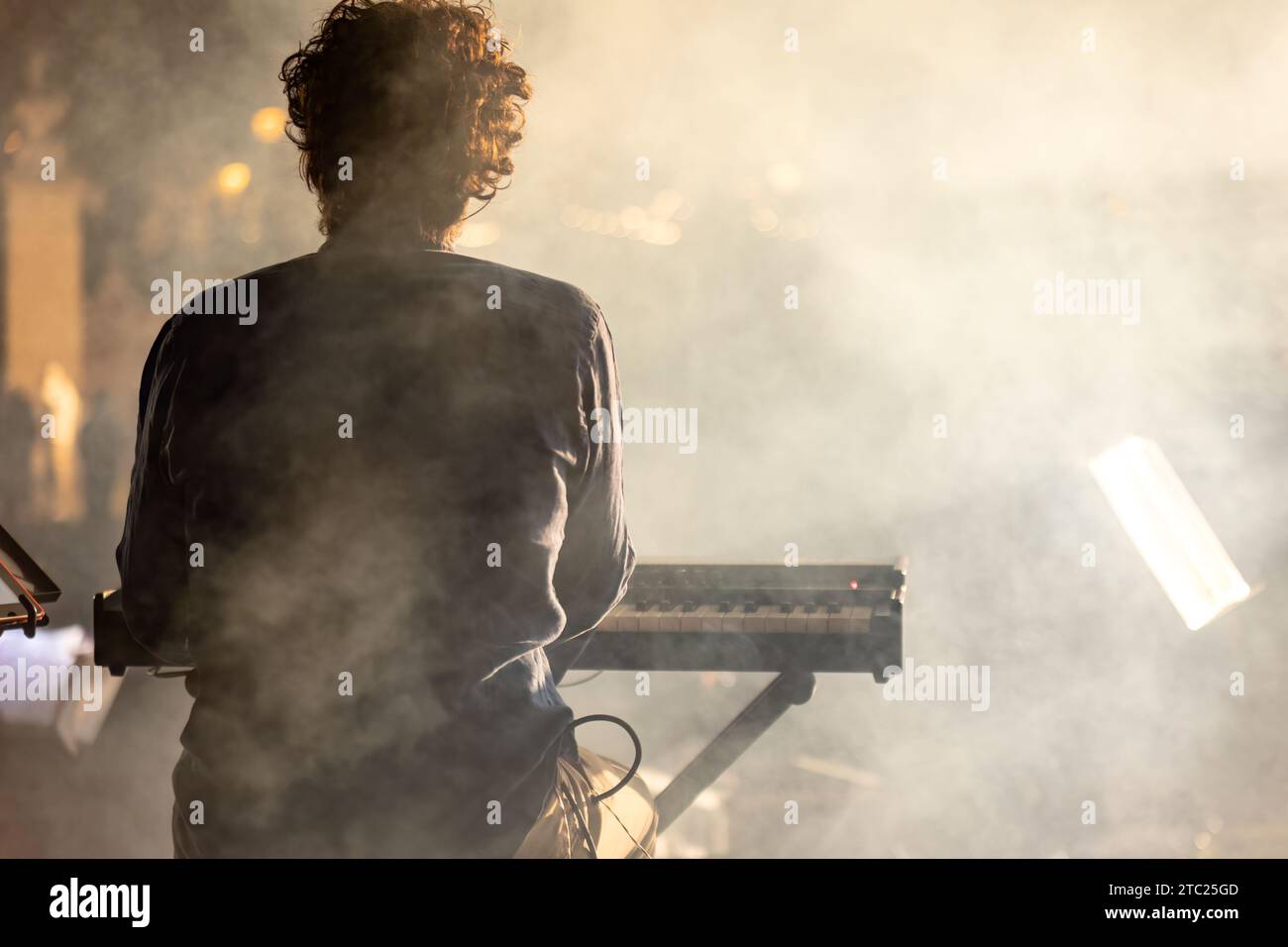 Un pianiste vu de derrière, jouant dans un concert de nuit avec une atmosphère brumeuse mystique. Banque D'Images