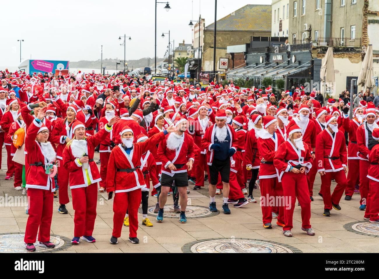 Plusieurs centaines de personnes toutes vêtues de vêtements rouges du Père Noël debout en plein air sur le front de mer à Herne Bay avant de prendre part à une course caritative, 'Santa's in the Bay' pour le Pilgrims Hospice. Banque D'Images