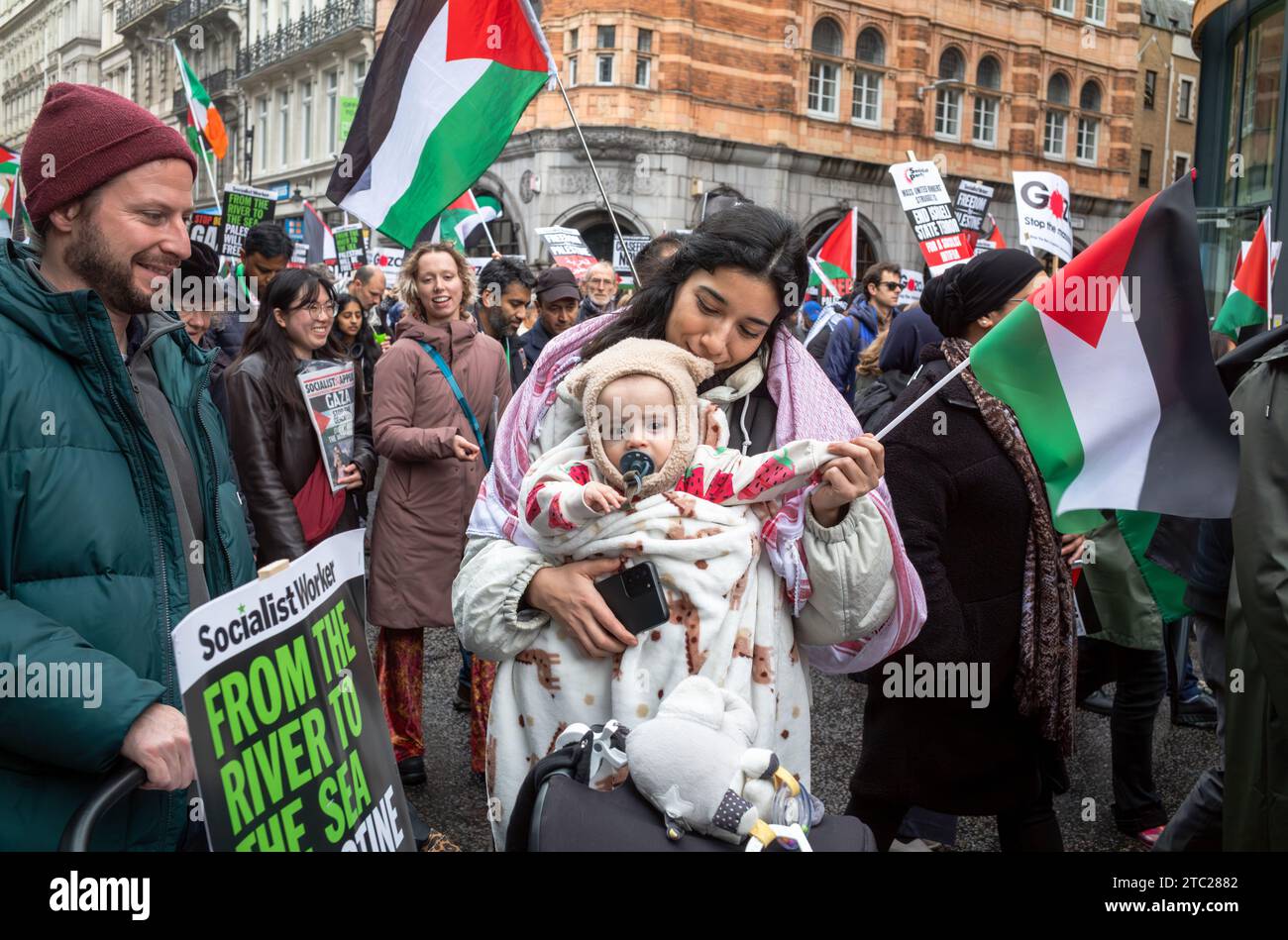 Londres, Royaume-Uni. 9 décembre 2023 : un jeune couple avec leur bébé et un drapeau palestinien lors d'une manifestation pro-palestinienne appelant à la fin des attaques israéliennes Banque D'Images