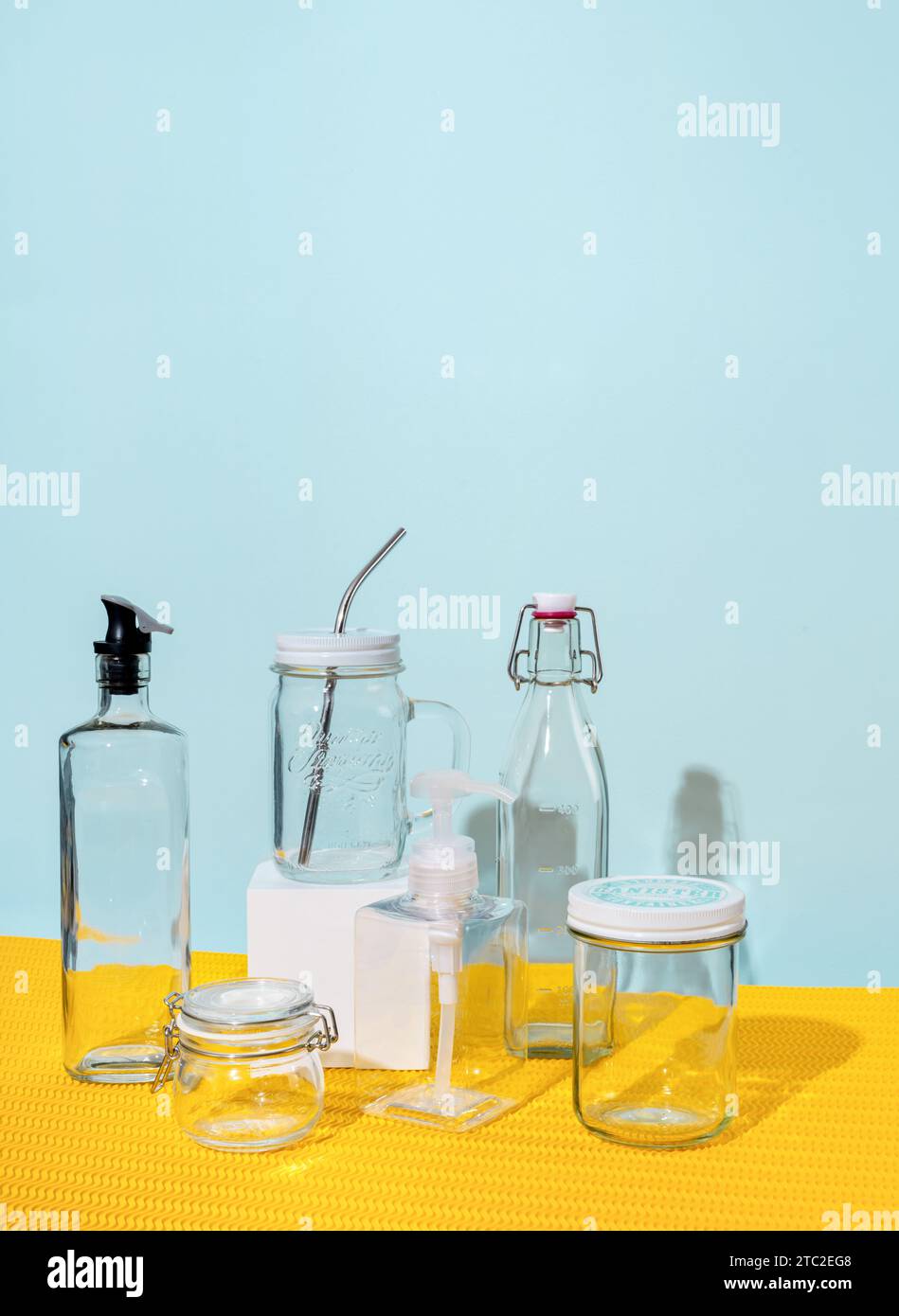 Les récipients en verre et les bouteilles d'eau reposent sur un fond jaune et menthe Banque D'Images