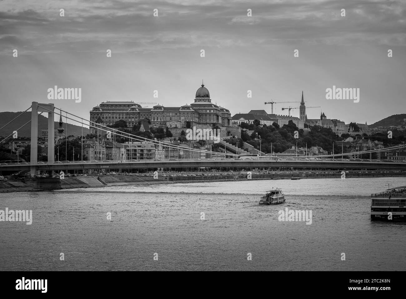 Budapest en noir et blanc : vue sur le Danube, le pont Elisabeth (Erzsébet híd) et le château de Buda (Budavári Palota), rayons du soleil à travers un ciel nuageux Banque D'Images