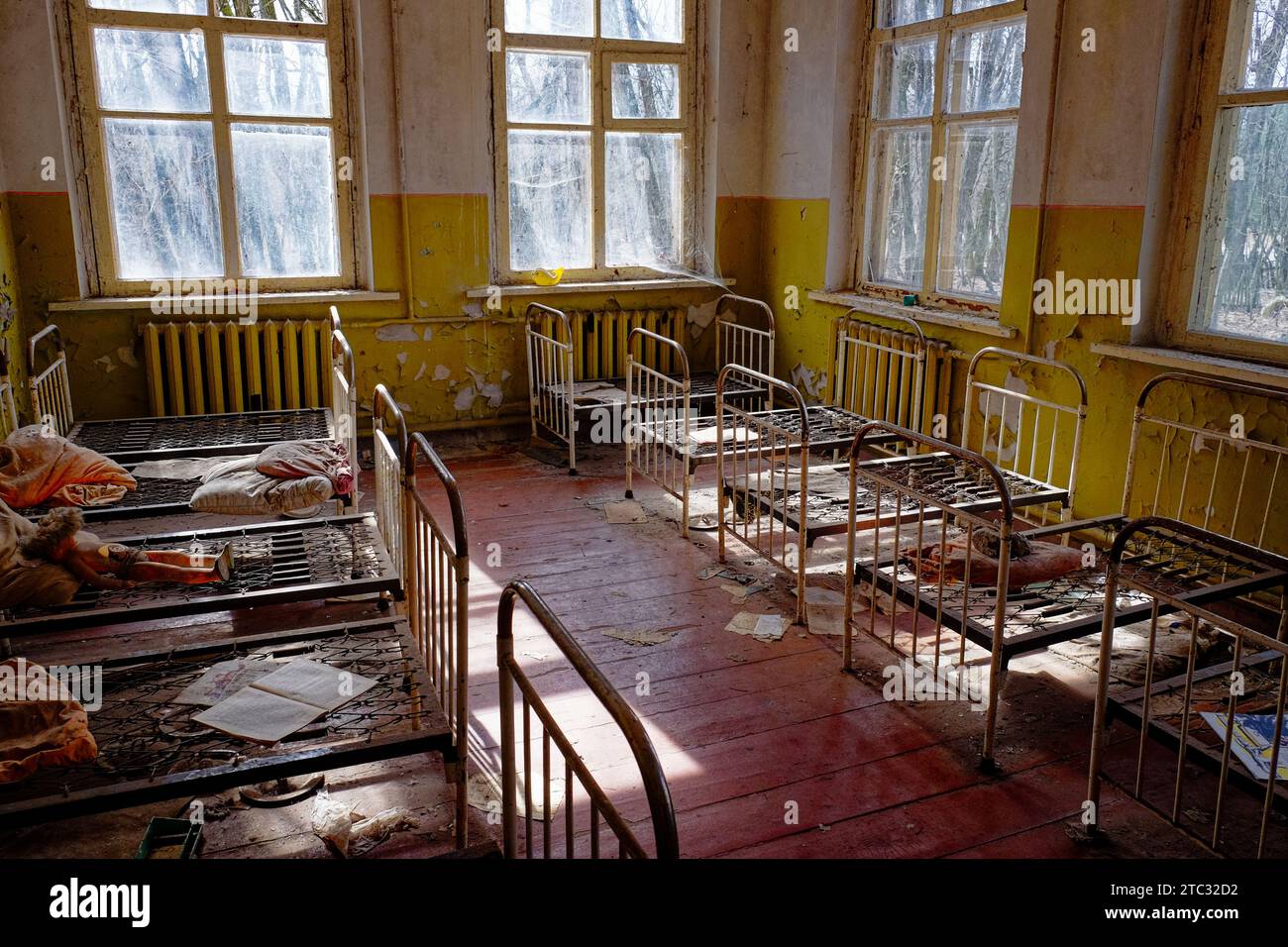 Une pièce négligée avec de la peinture jaune écaillée et un sol sale. Vieux lits d'enfants dans un jardin d'enfants abandonné. L'intérieur d'une pièce dans l'un des buil Banque D'Images