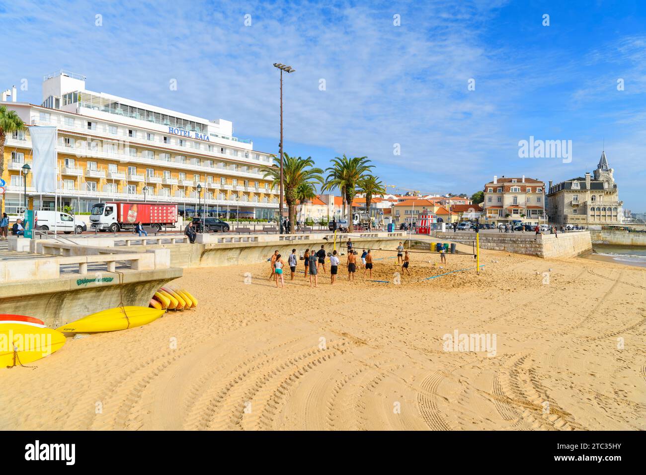 Un groupe de jeunes hommes et femmes actifs jouent au Beach volley dans le sable sur la plage de Praia da Ribeira à Cascais, Portugal. Banque D'Images