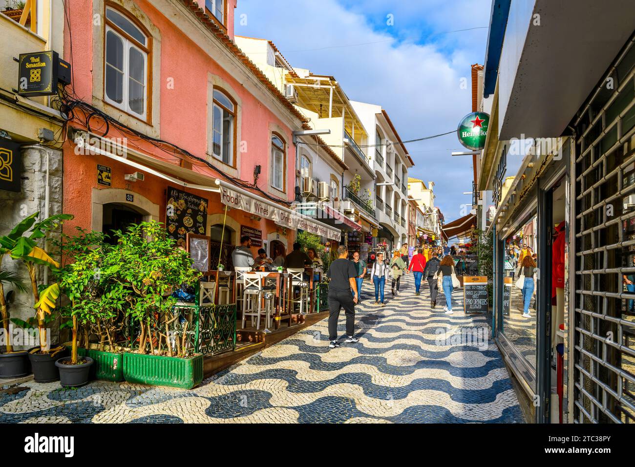 Une rue animée de boutiques et de cafés de trottoir avec des carreaux de pavé traditionnels Calcada en mosaïque dans la vieille ville de la ville balnéaire de Cascais, Portugal. Banque D'Images