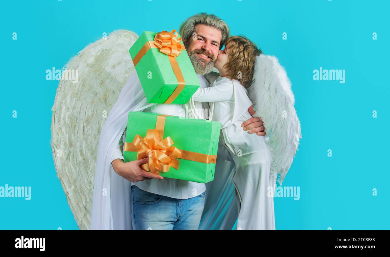 Valentines anges père et fils dans les ailes blanches avec boîte cadeau. Petit garçon cupidon et homme barbu souriant en costume d'ange avec des cadeaux Valentines Banque D'Images