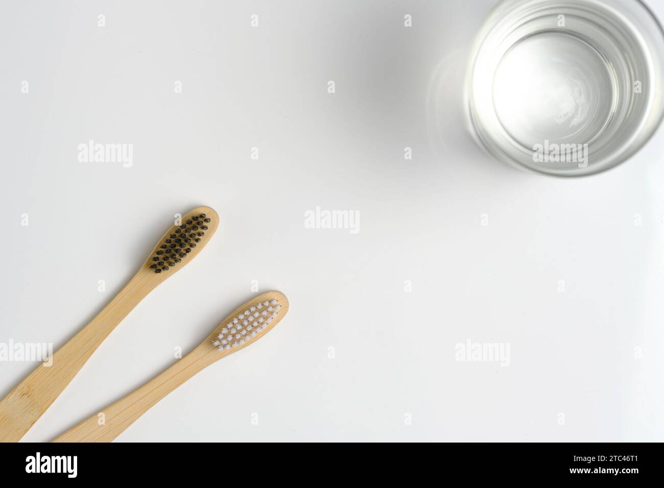 Eau en verre et deux brosses à dents en bois salle de bain sur fond blanc Banque D'Images