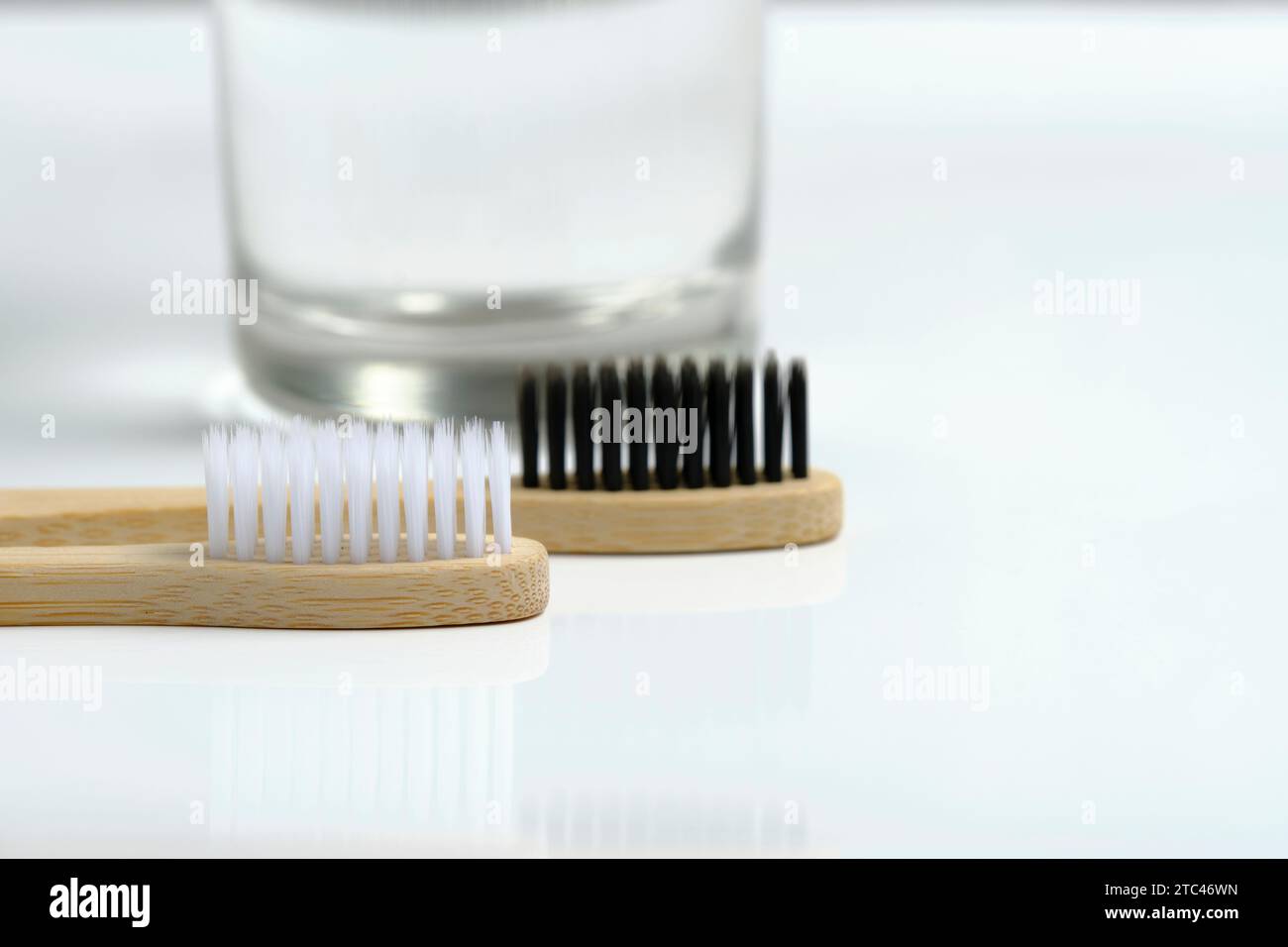 Eau en verre et deux brosses à dents en bois salle de bain sur fond blanc Banque D'Images