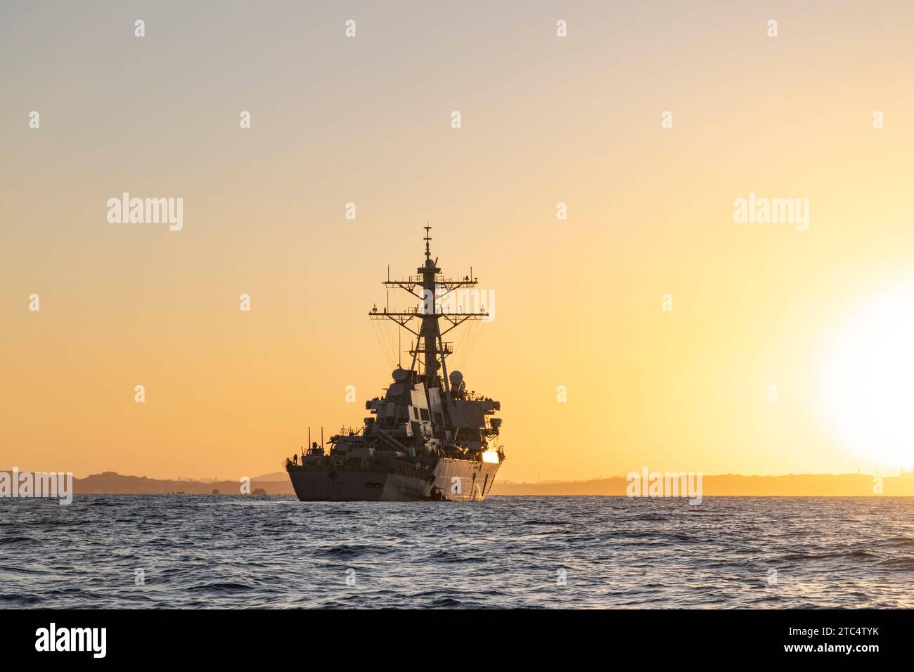 Le soleil se couche à côté de l'USS Hopper (DDG 70) à la suite d'une visite, d'un embarquement, d'une perquisition et d'un entraînement de saisie mené par les Marines américains avec la force de raid maritime, 31st Marine Expeditionary Unit, au large des côtes d'Okinawa, au Japon, le 8 décembre 2023. L'USS Hopper est un destroyer à missiles guidés de classe Arleigh Burke, affecté au Carrier Strike Group 1, déployé dans la zone d'opérations de la 7e flotte américaine. VBSS fait partie des opérations d'interception maritime qui visent à retarder, perturber ou détruire les forces ennemies ou les approvisionnements dans le domaine maritime. La 31e MEU, la seule MEU du corps des Marines déployée en continu, pr Banque D'Images