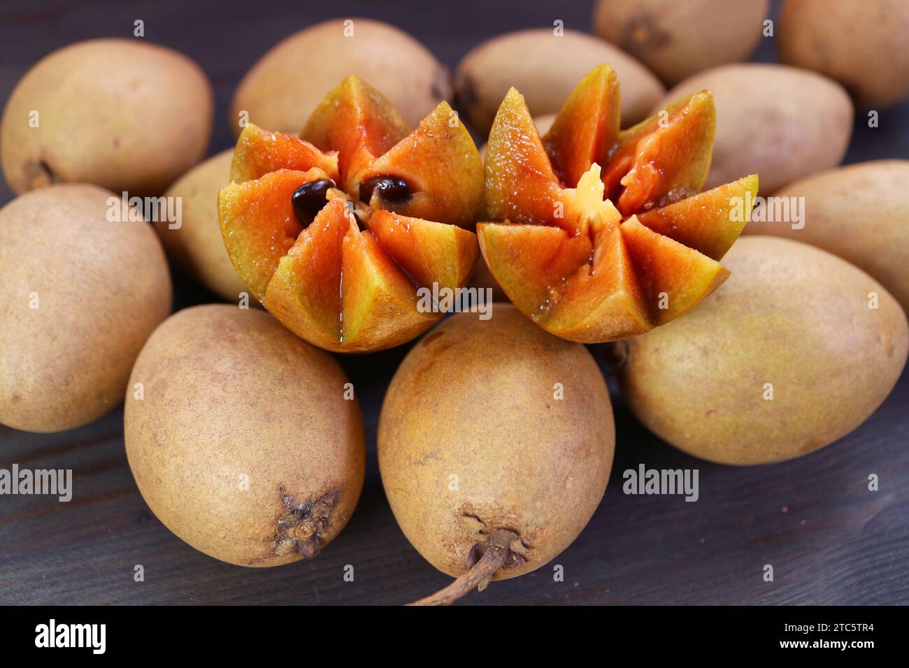 Magnifiquement couper Sapodilla fruit et tas de fruits entiers sur fond en bois noir Banque D'Images