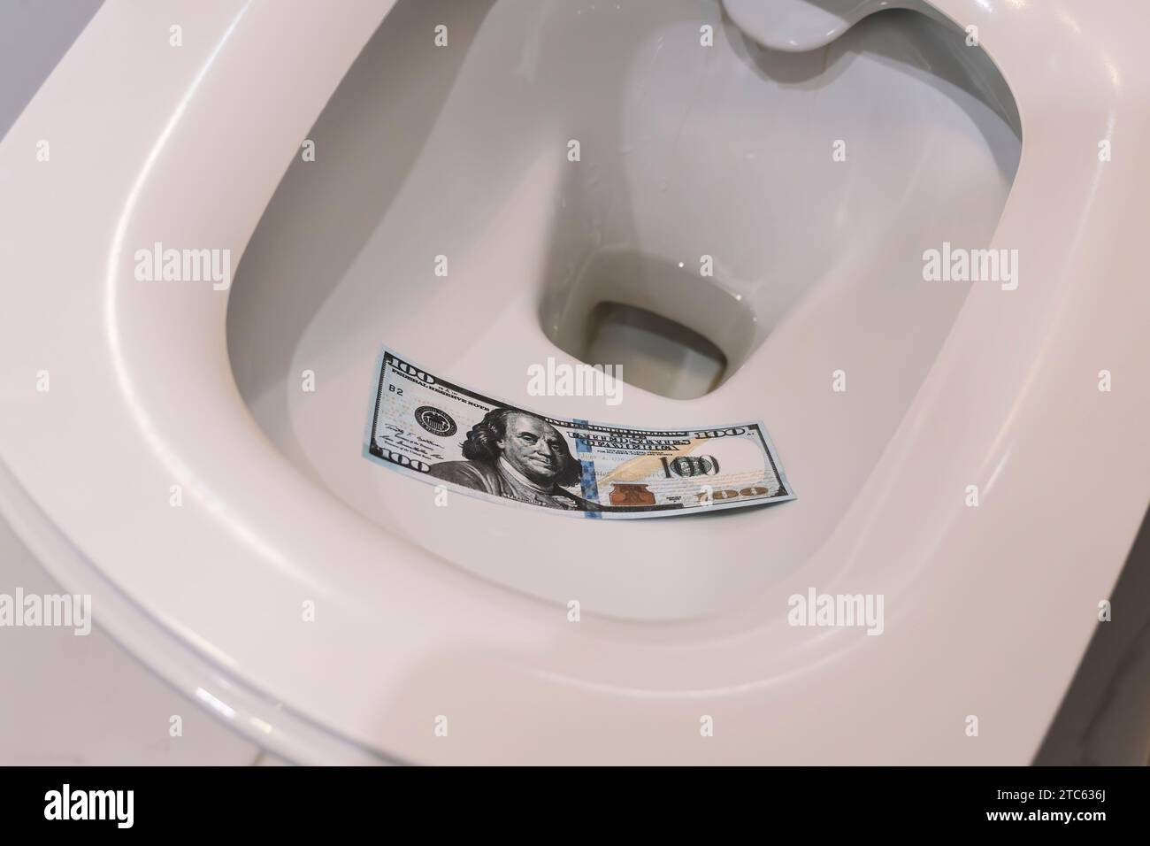 Dollars dans les toilettes. Les dollars sont utilisés à la place du papier toilette, jetés dans les toilettes et rincés dans les toilettes. toilettes à chasse d'eau. Crise du dollar américain Banque D'Images