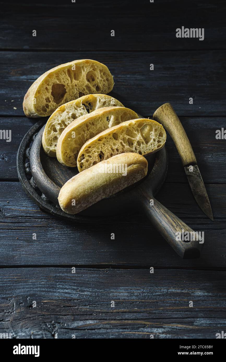 Tranches de petit pain ciabatta sur une table rustique sombre Banque D'Images