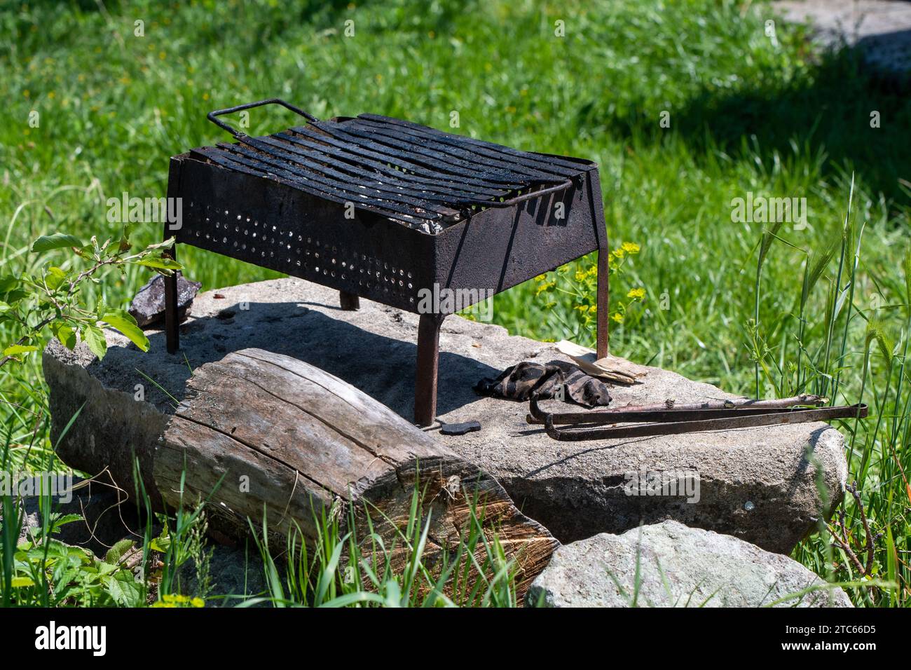 Vieille plaque de gril en métal noir. Pour barbecue. Champ d'herbe verte. Nature, environnement. Pique-nique. Après utilisation. Banque D'Images