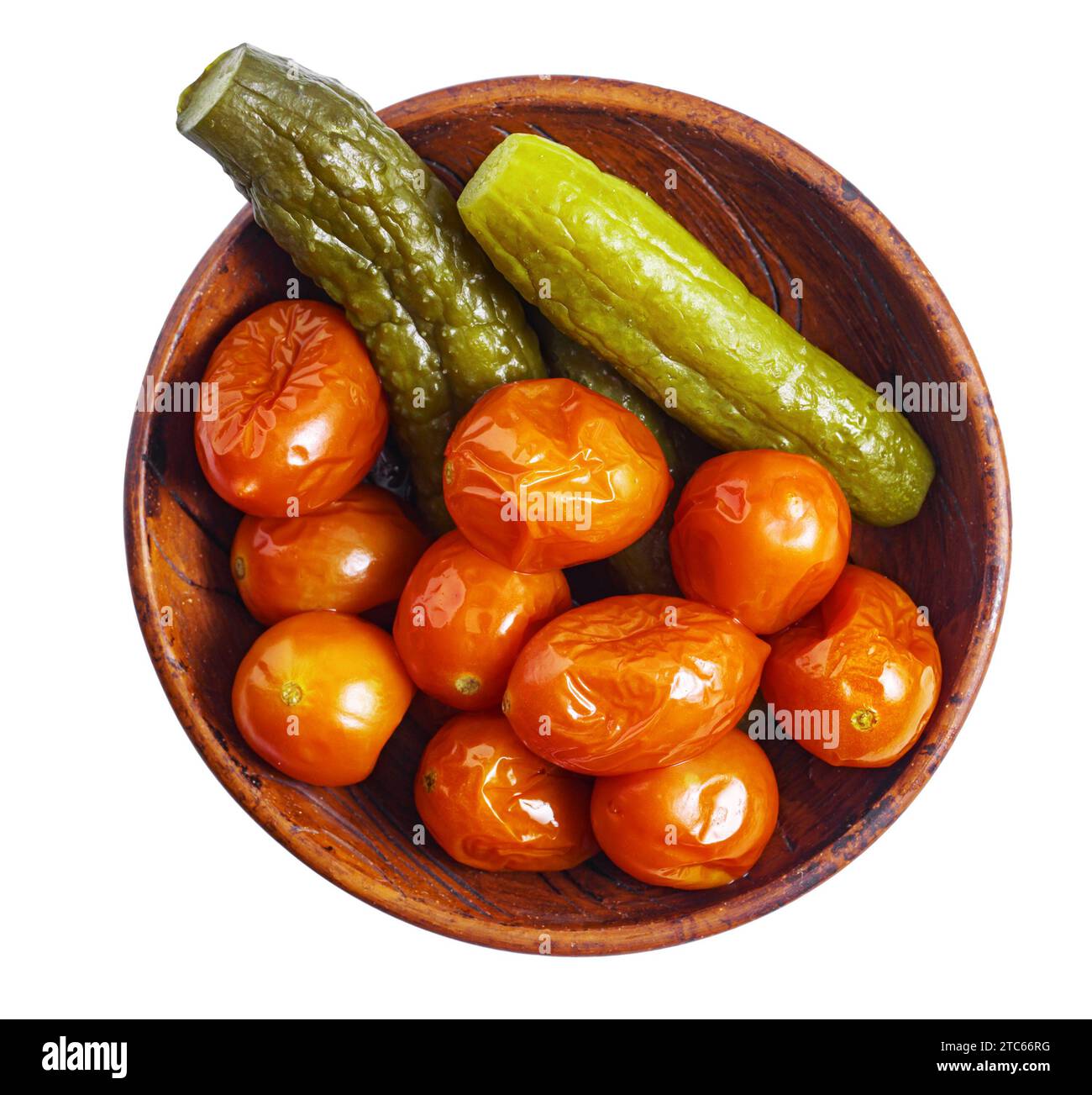 Petites tomates et concombres marinés dans un bol rustique en céramique, vue de dessus, isolé Banque D'Images