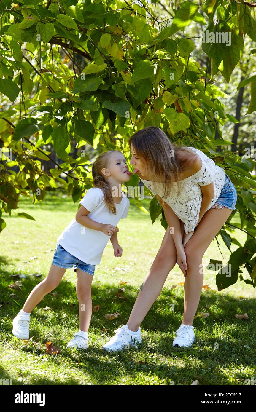 Mère et fille marchent dans le parc de la ville d'été. Enfance, loisirs et concept de personnes - famille heureuse repose sur la nature et passe un bon moment Banque D'Images