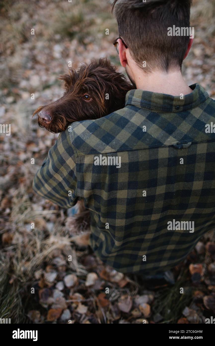 Homme tenant un chien Griffon sur l'épaule dans la forêt Banque D'Images