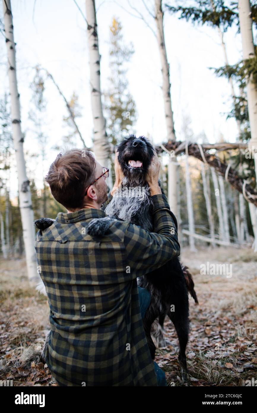 Moment joyeux comme l'homme embrasse son chien noir dans la forêt Banque D'Images