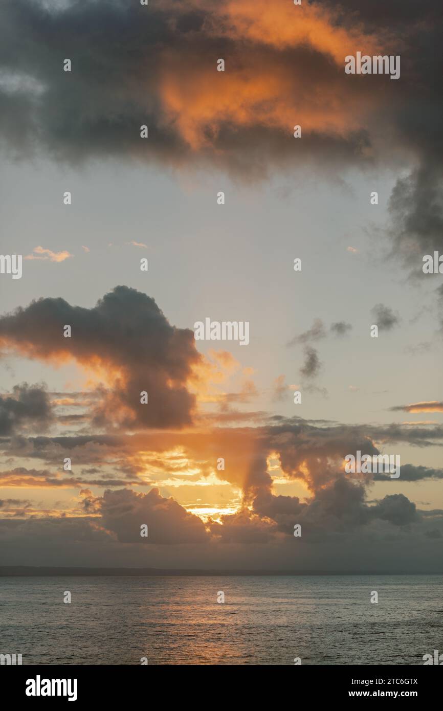 Coucher de soleil sur l'océan dominicain : nuages orange vibrants, eaux tranquilles. Banque D'Images