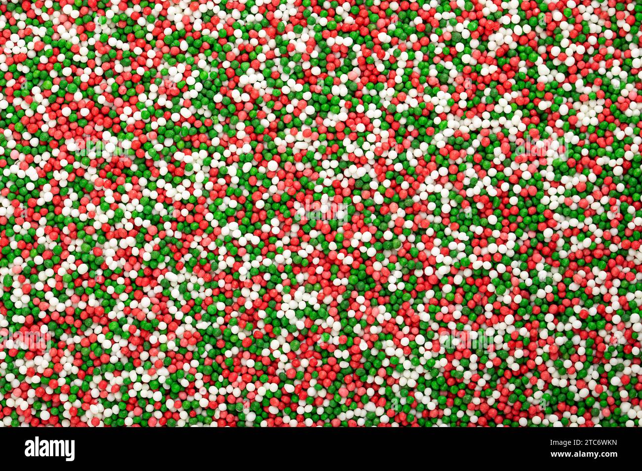 Saupoudrages colorés faits de minuscules boules de sucre. Mélange vert, rouge et blanc de nonpareils. Des centaines et des milliers décoratifs faits de sucre et d'amidon. Banque D'Images