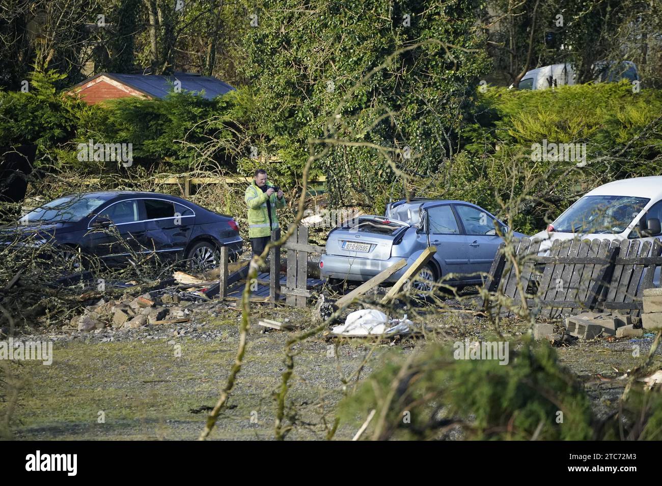 Un homme prend une photo d'une voiture endommagée dans le village de Leitrim à Co Leitrim, après une tornade et des vents violents sur des arbres aplatis dimanche, arraché un toit d'un bâtiment et laissé des débris éparpillés dans une rue. Date de la photo : lundi 11 décembre 2023. Banque D'Images