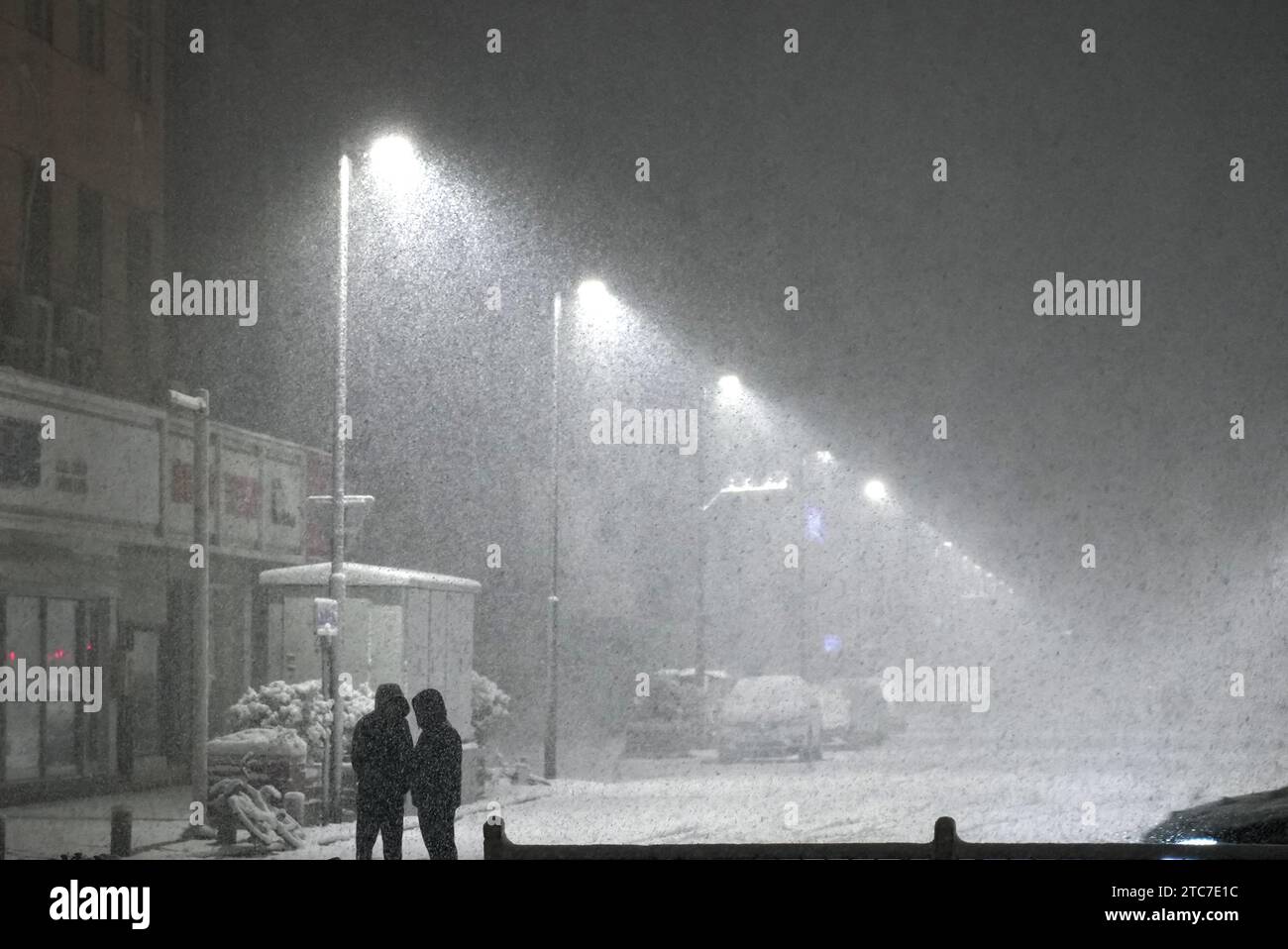 Zhengzhou, province chinoise du Henan. 11 décembre 2023. Les gens se tiennent dans une rue au milieu de la neige abondante à Zhengzhou, dans la province du Henan, au centre de la Chine, le 11 décembre 2023. Les blizzards ont frappé la province centrale du Henan en Chine, avec des écoles suspendues et des vols annulés dans la capitale provinciale Zhengzhou lundi matin. En six heures, de la fin du dimanche au début du lundi, les précipitations à la station de Zhengzhou ont atteint 14,2 mm et la neige accumulée a atteint 10 cm, selon la station météorologique de la ville. Crédit : Wu Gang/Xinhua/Alamy Live News Banque D'Images