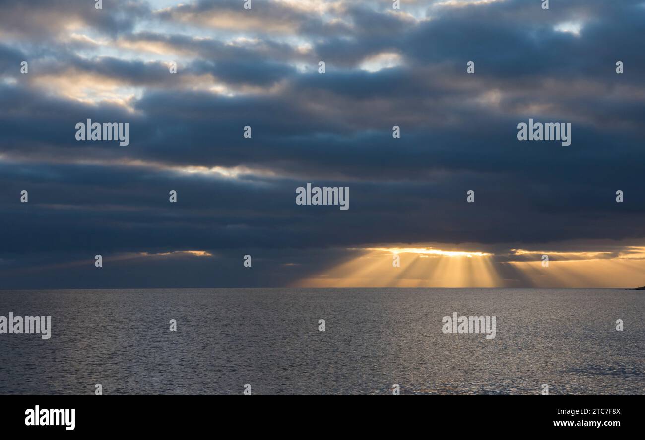 rayons de soleil brillant à travers gap dans des nuages noirs sombres sur l'horizon de la mer. Hiver, novembre, Devon, Royaume-Uni Banque D'Images