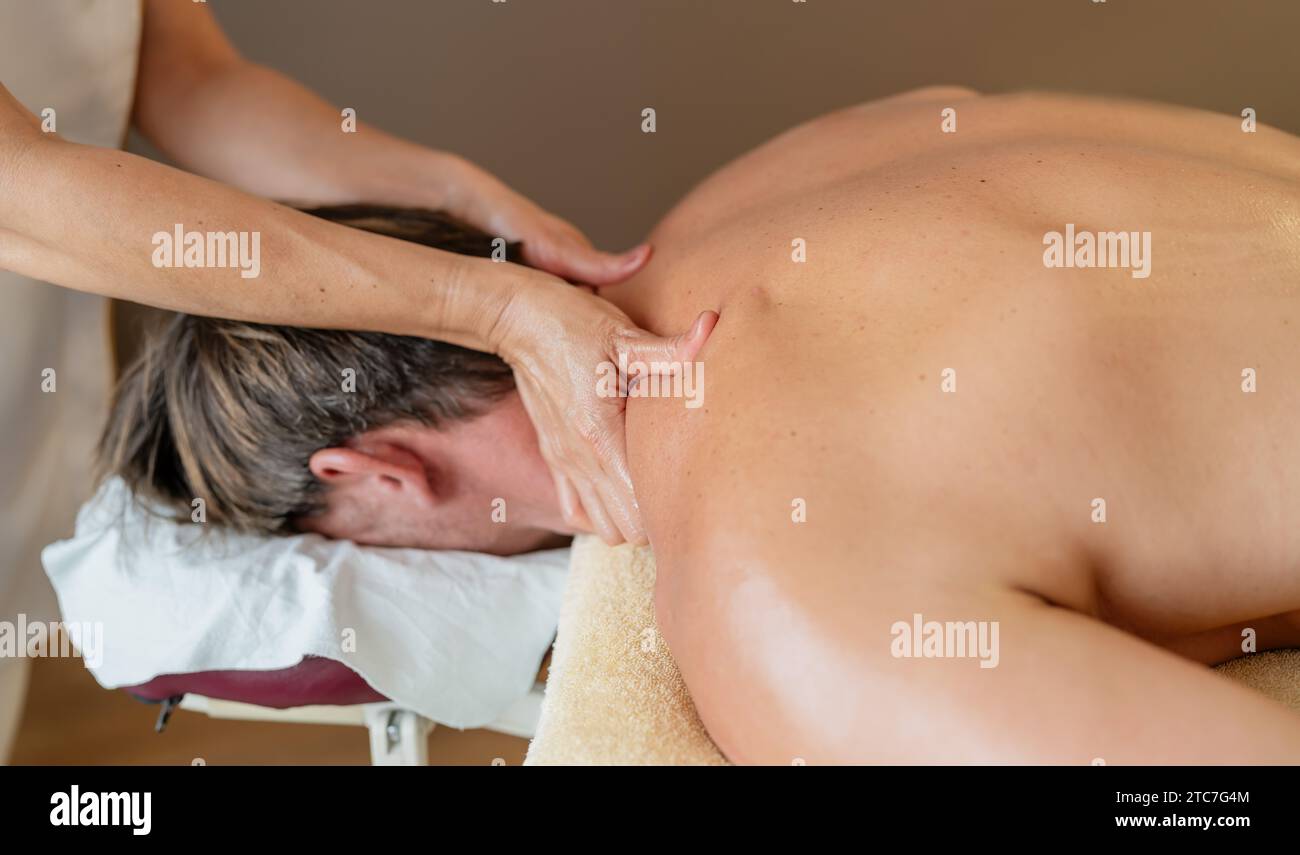 Thérapeute appliquant un massage du cou à un client masculin dans un cadre paisible de spa. Image conceptuelle de l'hôtel Wellness Banque D'Images