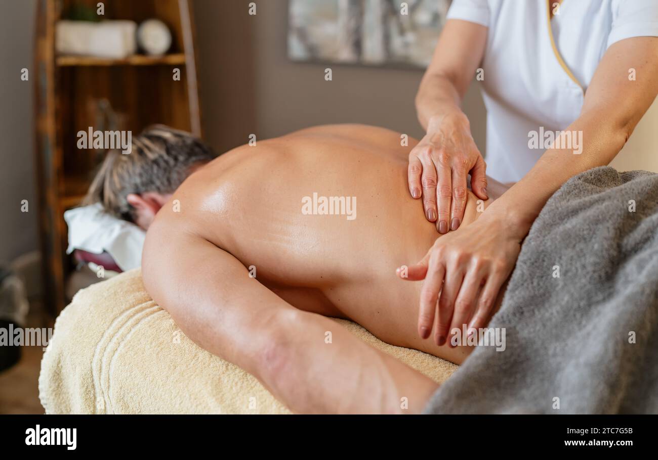 Massothérapeute effectuant un massage du dos sur le client masculin dans le spa. Image conceptuelle de l'hôtel Wellness Banque D'Images