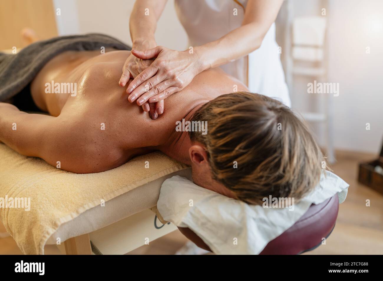 Thérapeute donnant un massage profond des tissus du dos à un client masculin dans un centre thermal ou un salon de beauté Banque D'Images