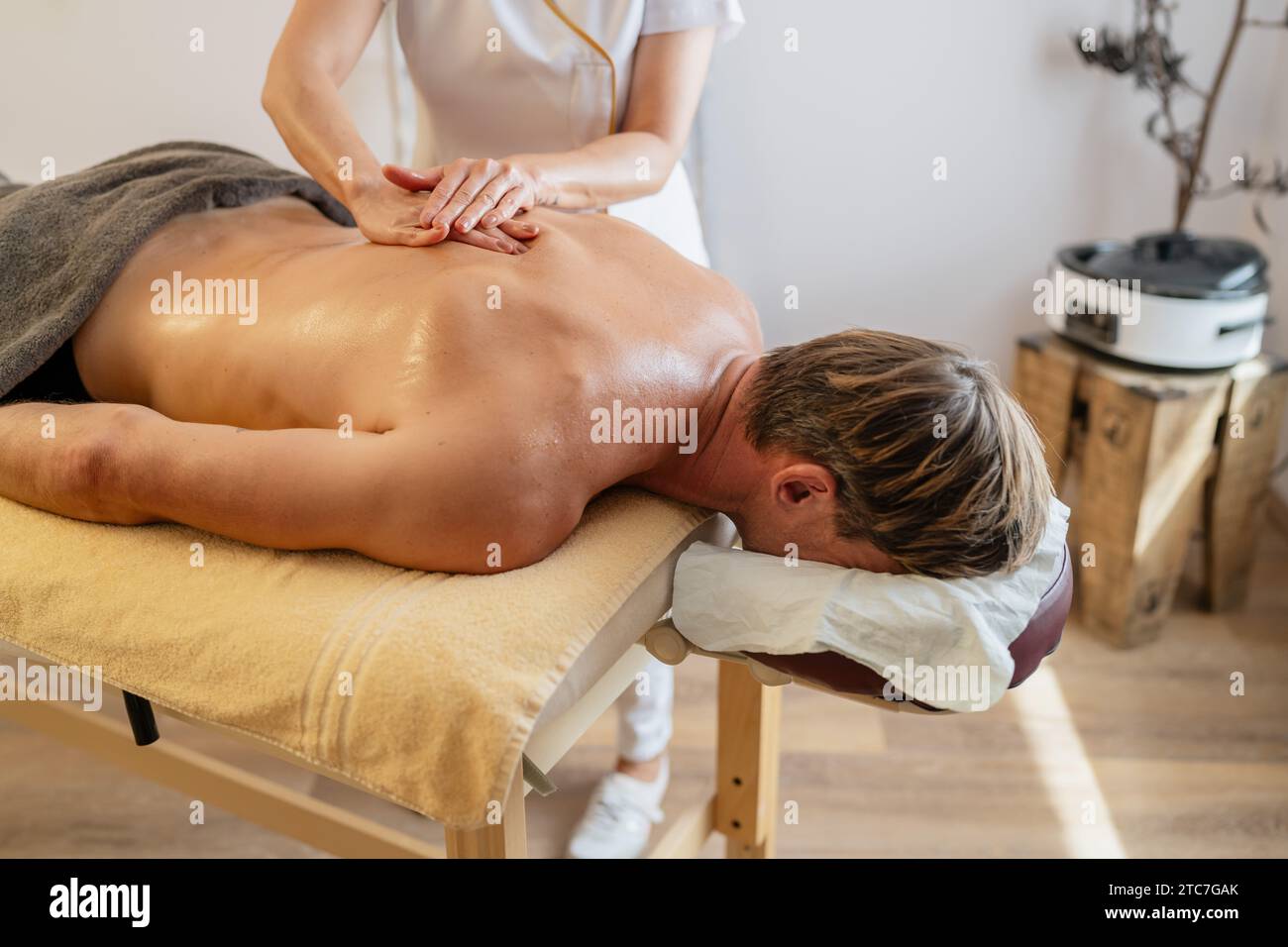 Client masculin recevant un massage du dos d'un thérapeute dans un hôtel spa moderne Banque D'Images