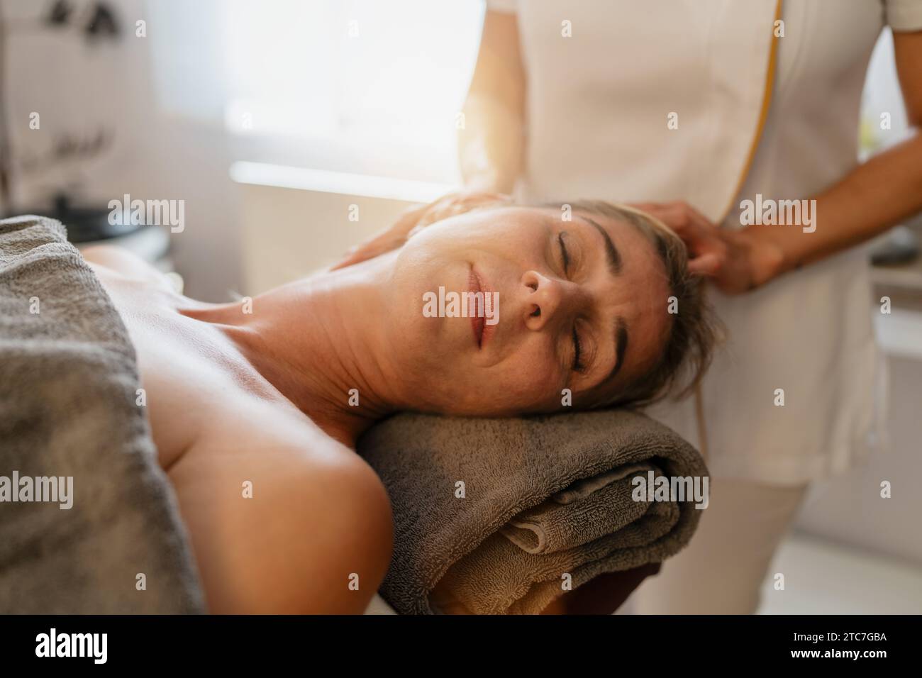 Thérapeute offrant un massage du cou à une cliente détendue dans un hôtel spa Banque D'Images