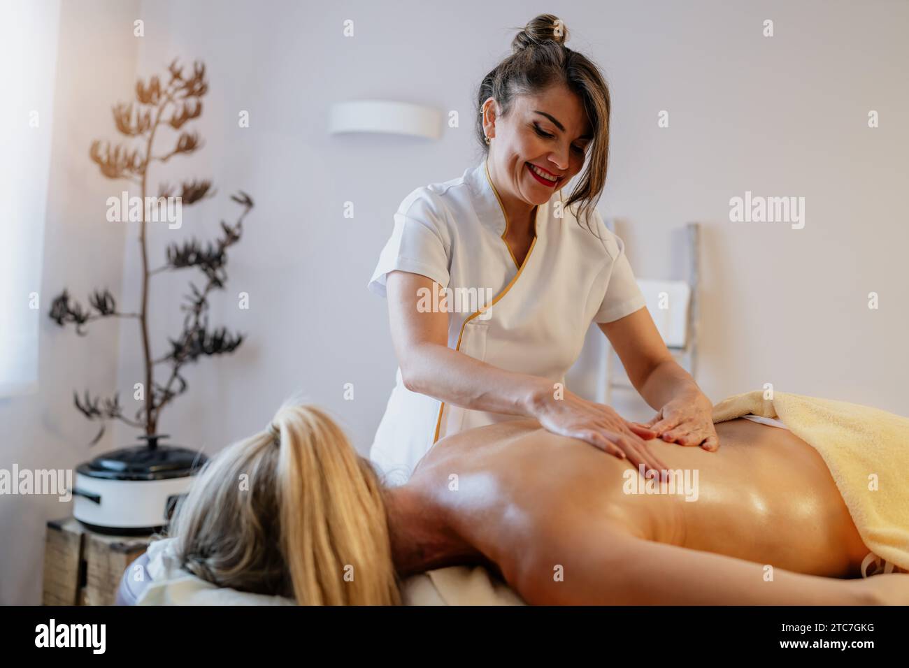 Massothérapeute asiatique souriant donnant un massage du dos à un client détendu dans un complexe hôtelier spa Banque D'Images