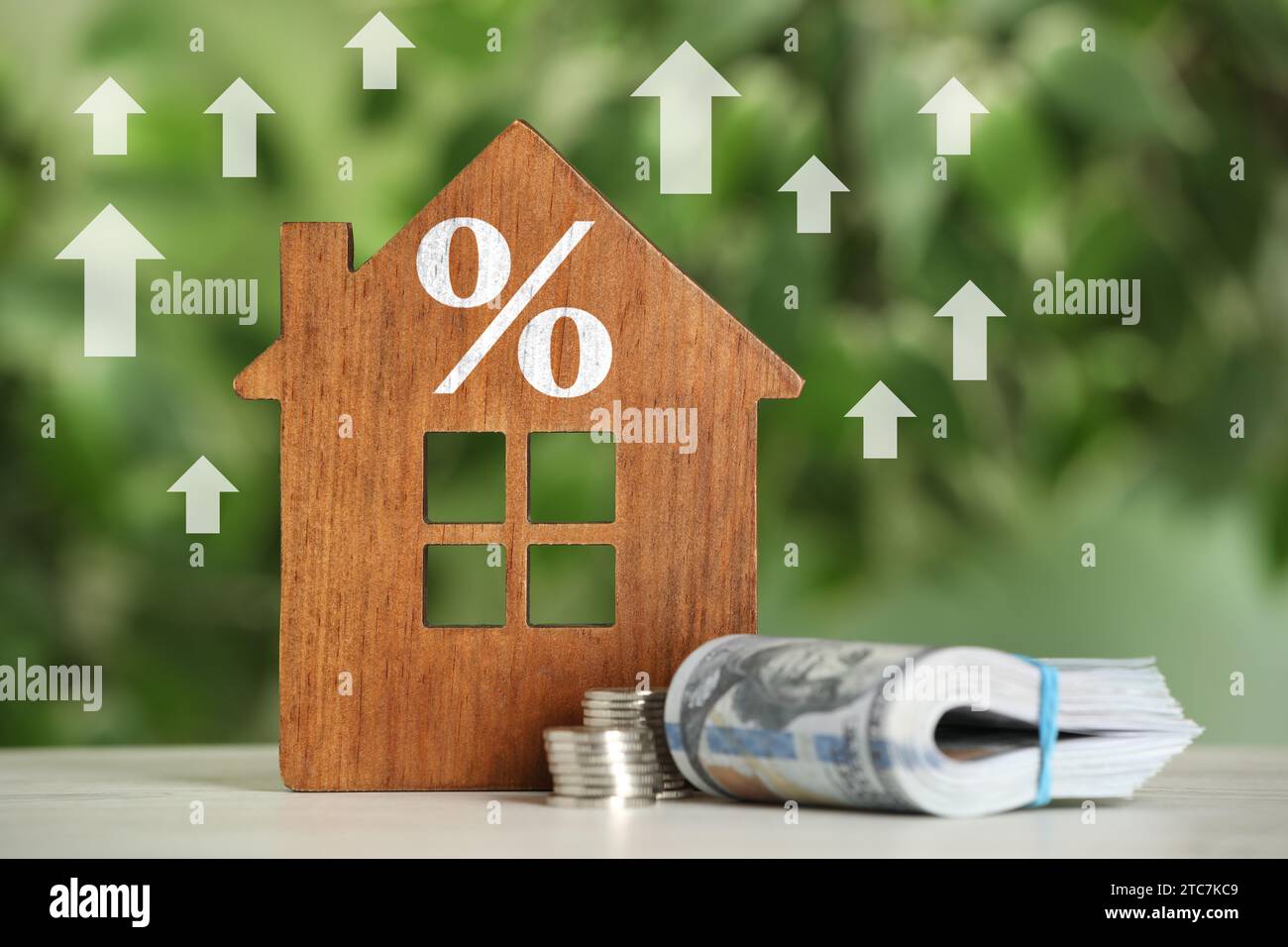 Hausse du taux hypothécaire illustrée par des flèches ascendantes et un signe de pourcentage. Modèle de maison et argent sur la table Banque D'Images