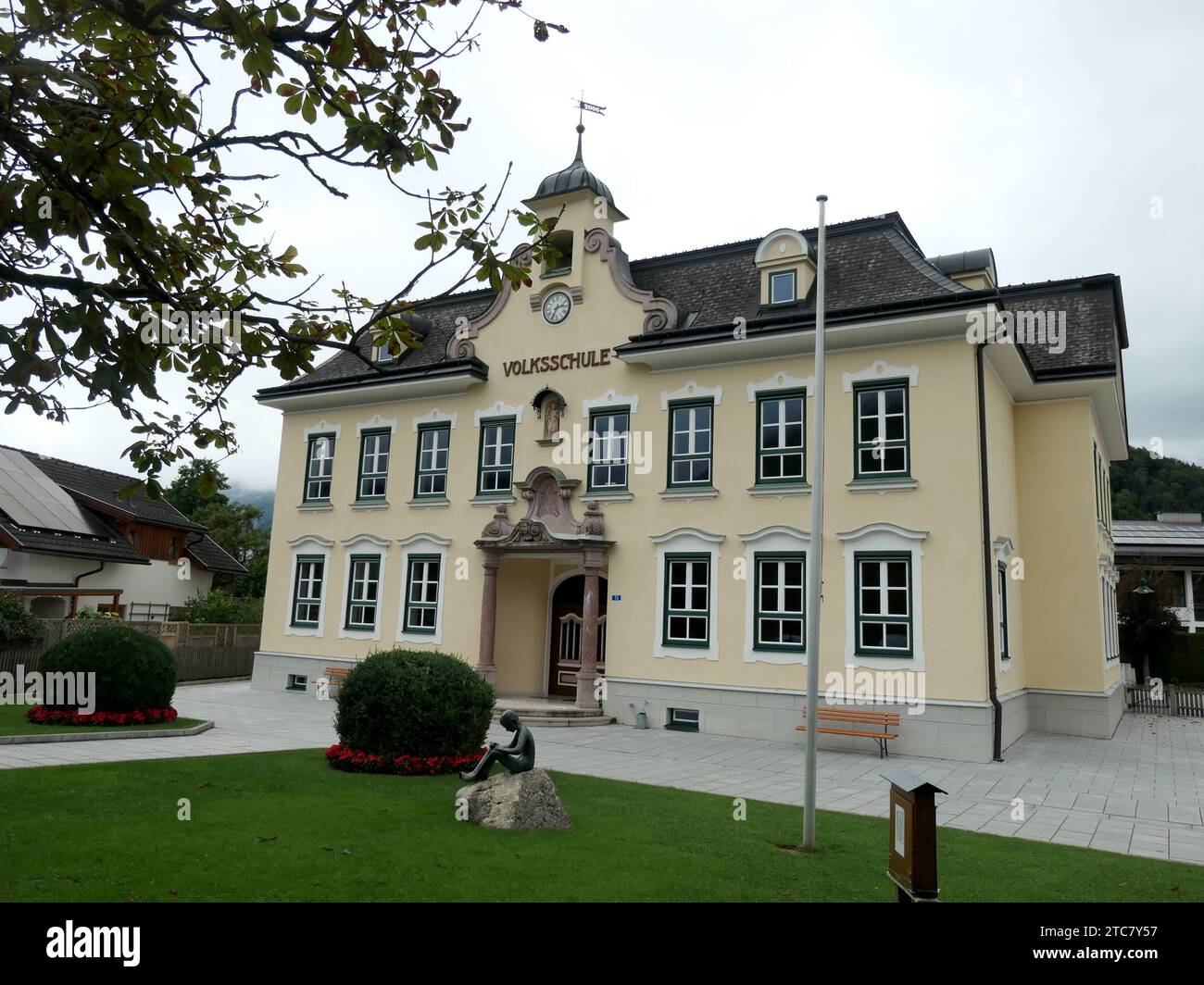Strobl, Autriche. 27 août 2023. L'école primaire Strobl à Strobl am Wolfgangsee dans la région du Salzkammergut en Autriche. La sculpture en bronze 'Reading Boy' se dresse devant l'école primaire. Le Salzkammergut est la capitale de la culture 2024. Crédit : Beate Schleep/dpa/Alamy Live News Banque D'Images