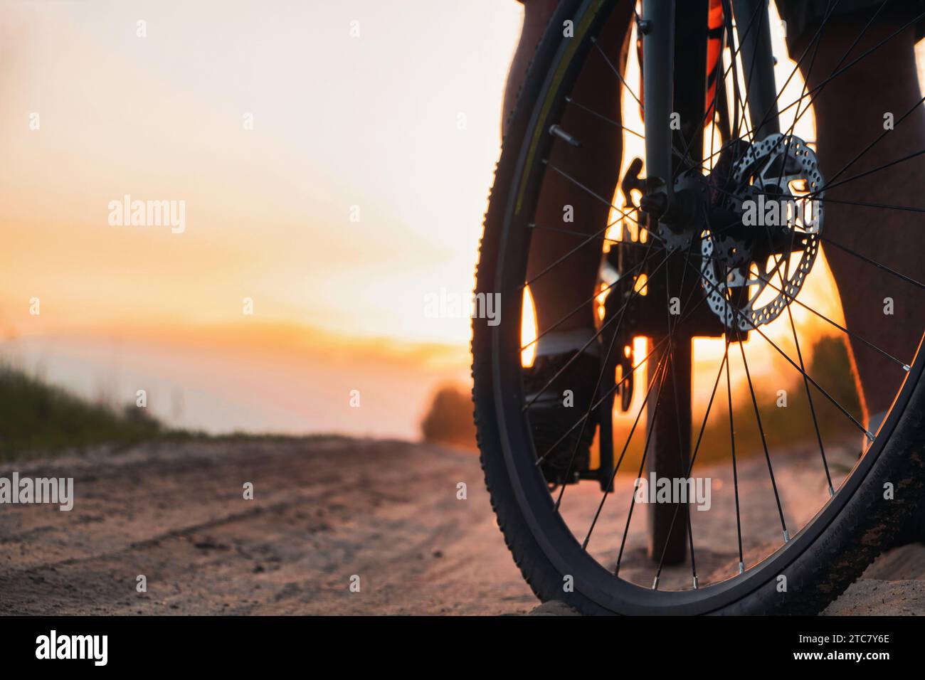 Gros plan de la roue avant du vélo sur un sentier sur fond de coucher de soleil. Cyclisme en plein air. Banque D'Images