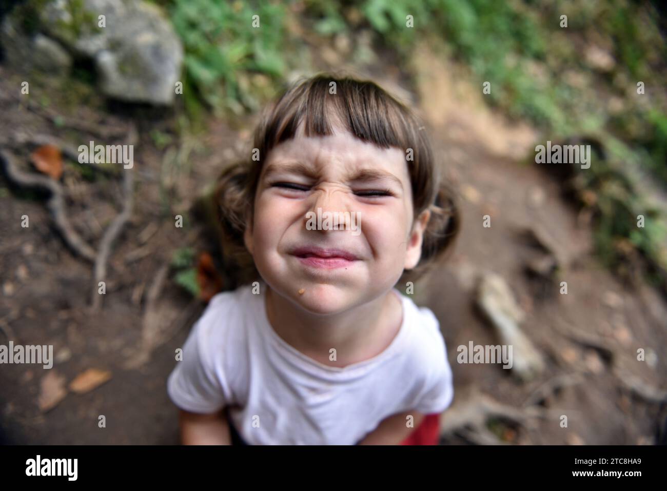Adorable bébé fille en bas âge faisant une grimace dans la forêt Banque D'Images