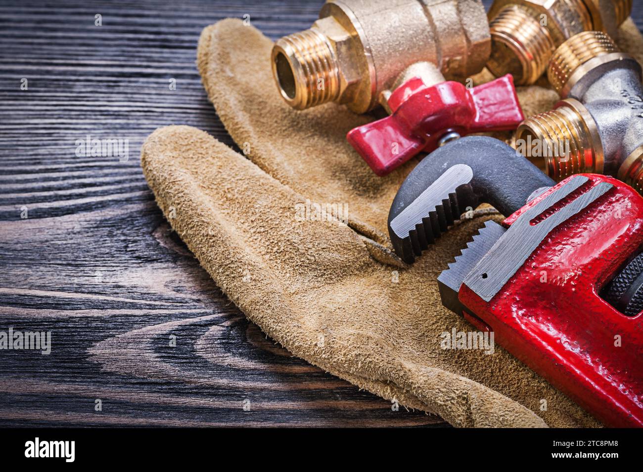 Gants de sécurité en cuir Monkey CLE connecteurs de plomberie en laiton sur planche de bois Banque D'Images