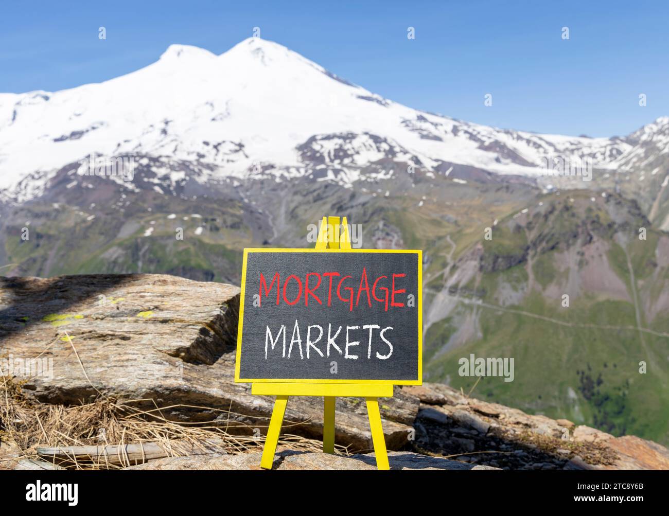 Symbole du marché hypothécaire. Mots concept marchés hypothécaires sur beau tableau noir de craie. Belle montagne Elbrus fond de ciel bleu. M Banque D'Images