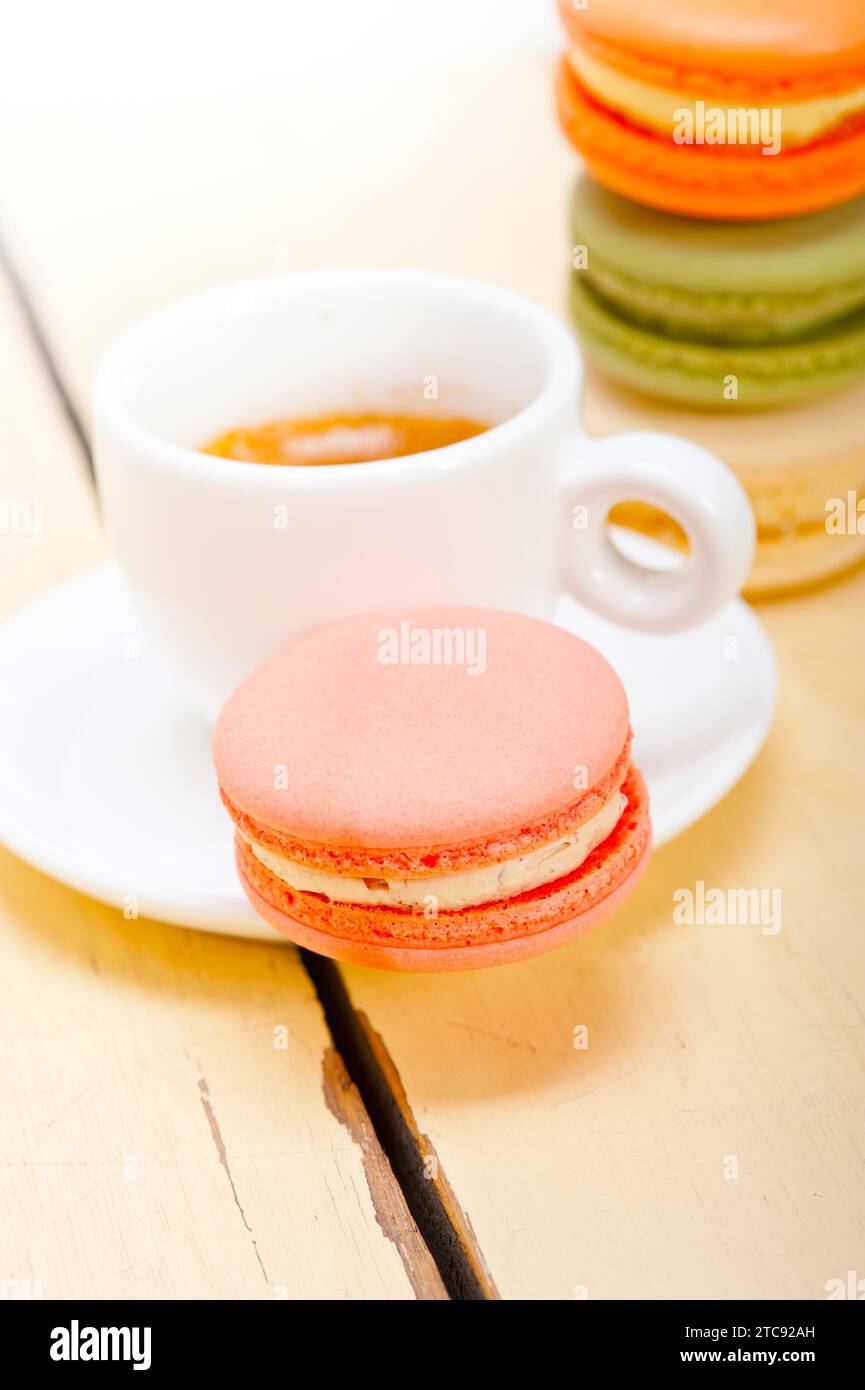 Macarons colorés avec café expresso sur table en bois blanc Banque D'Images