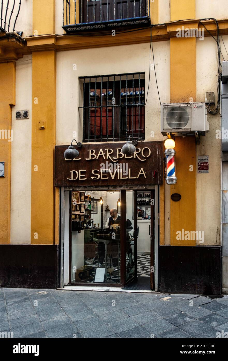 Entrée traditionnelle d'un salon de coiffure à Séville, en Espagne, avec un poteau rayé emblématique, avec un nom d'opéra. Banque D'Images