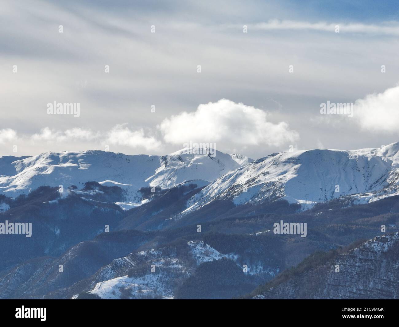 Skieur professionnel descendant une montagne en pente dans un paysage alpin immaculé, avec des montagnes enneigées en arrière-plan Banque D'Images