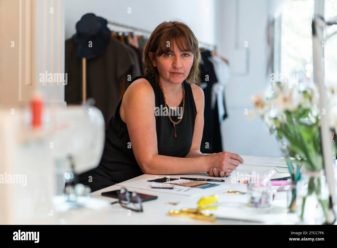 Créatrice de mode féminine regardant la caméra tout en se penchant sur son bureau dans son studio Banque D'Images