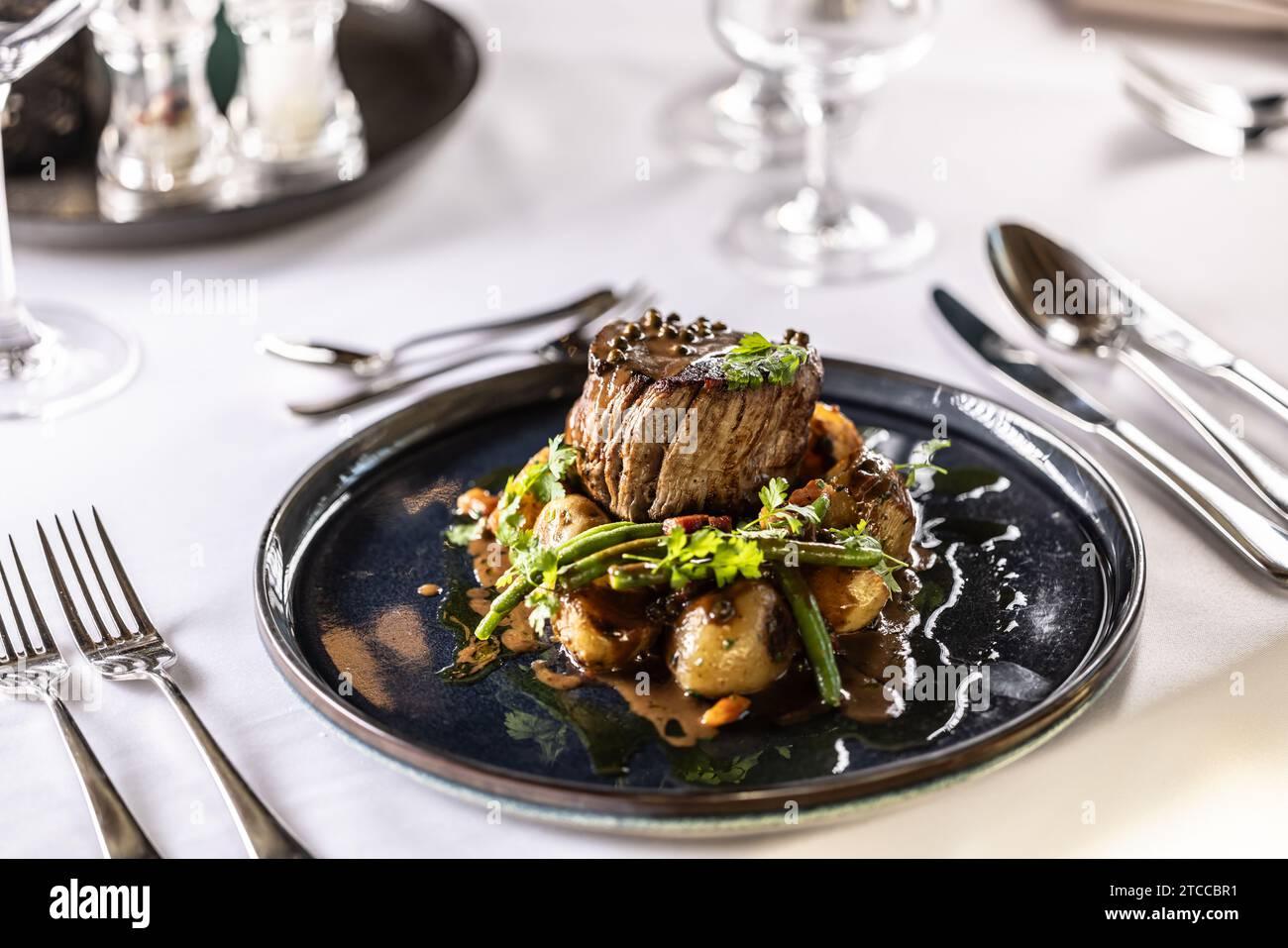 Steak de filet de filet de bœuf, haricots verts sautés au bacon, pommes de terre cuites et sauce au poivre vert. Steak de filet servi sur une assiette sur un festif Banque D'Images