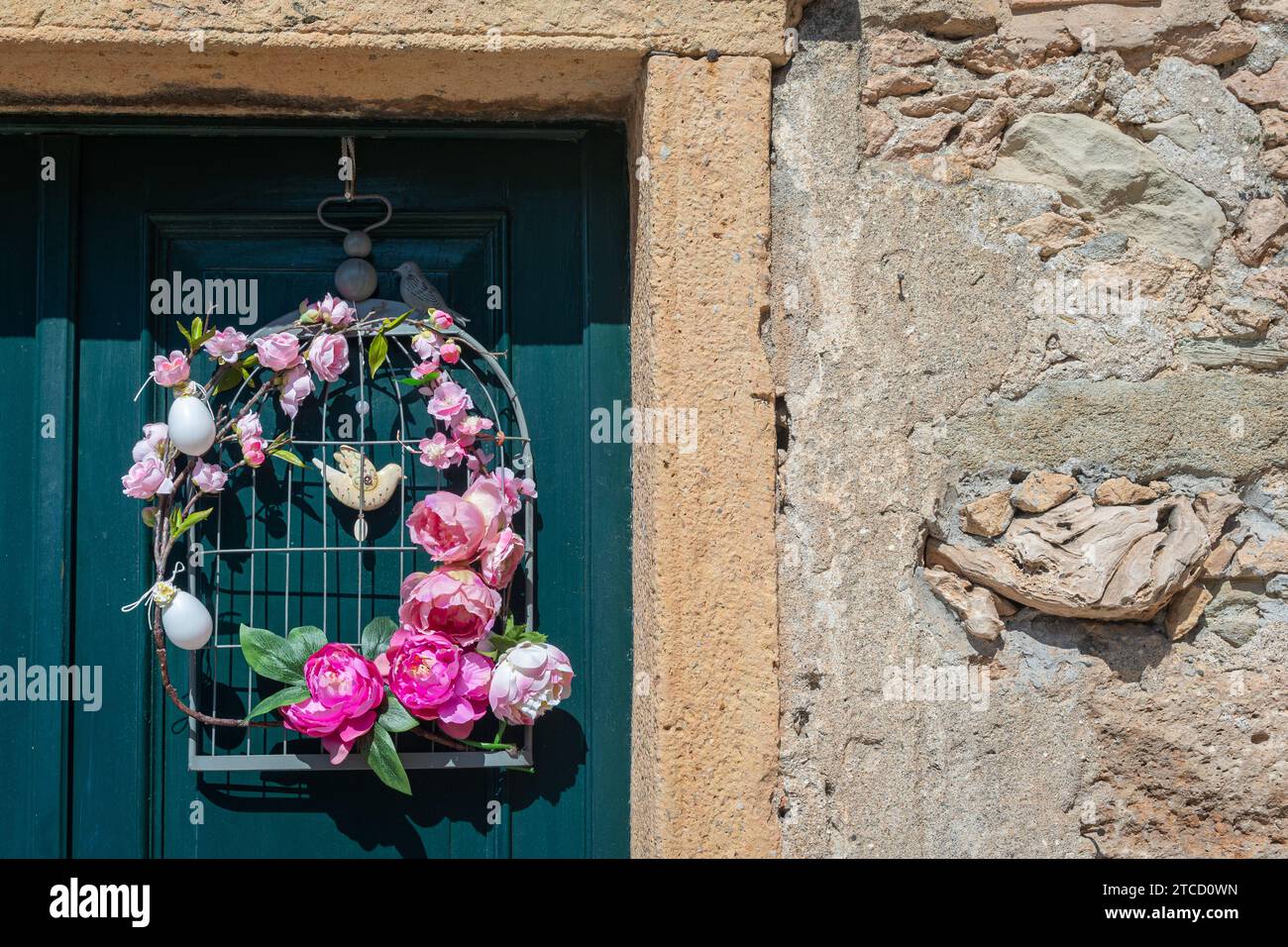 Décoration de Pâques avec des fleurs, des œufs et des oiseaux suspendus à la porte verte d'une maison en pierre, Italie Banque D'Images