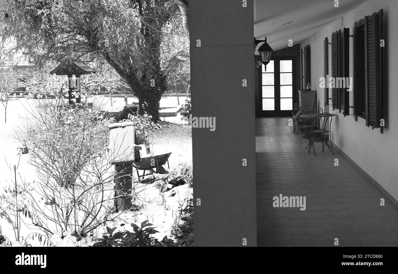 Image en noir et blanc d'une véranda et jardin d'une ancienne maison paysanne hongroise traditionnelle dans la neige, Szigethalom, Hongrie Banque D'Images