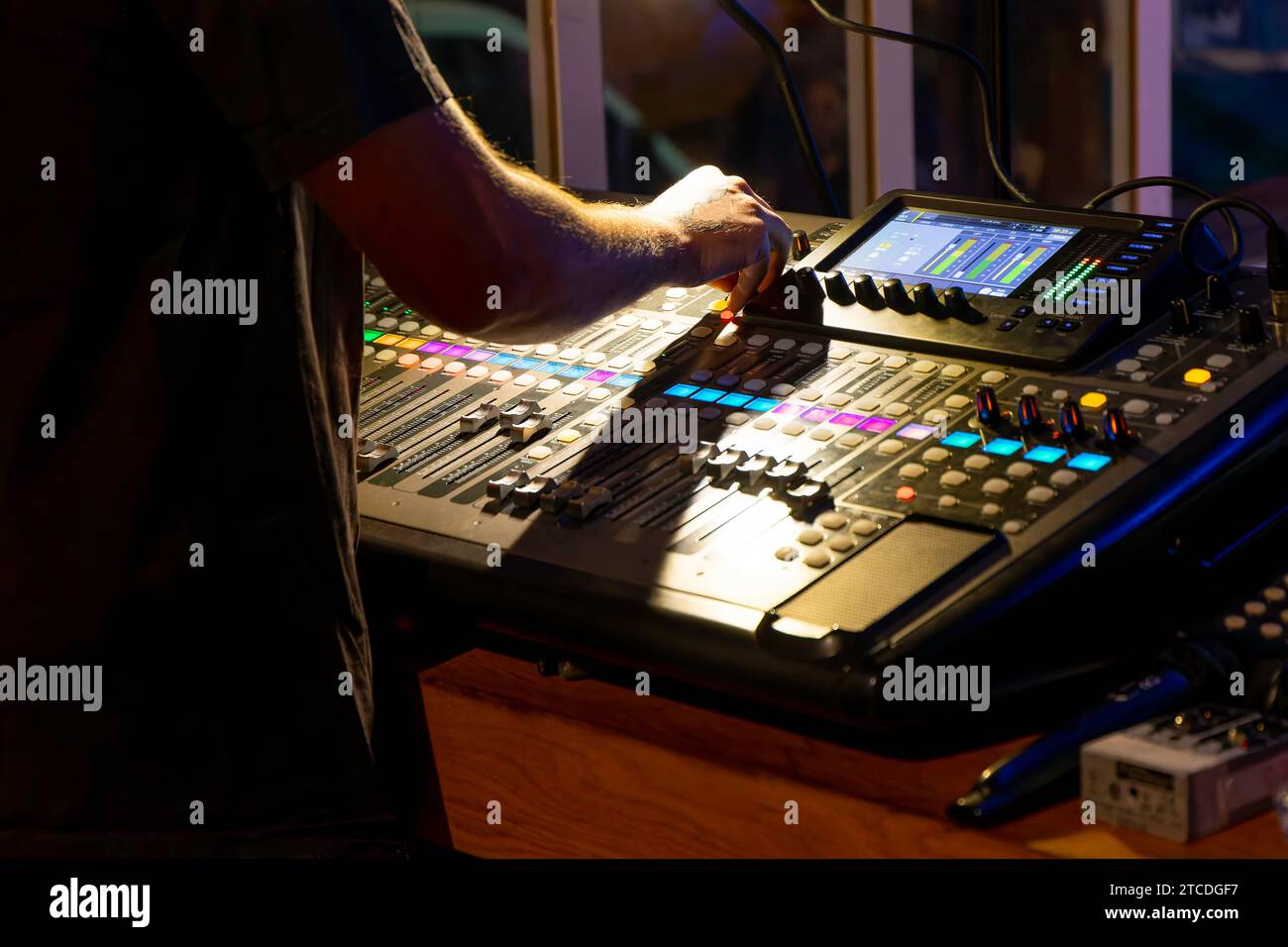 technicien du son méconnaissable réglant les niveaux sur une console de mixage multipiste dans la salle de contrôle pendant un événement Banque D'Images