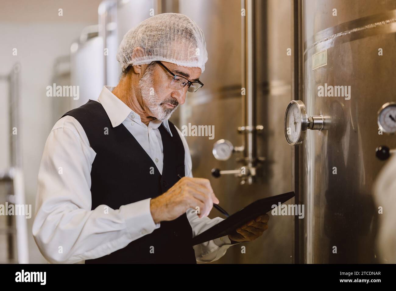 Viticulteur professionnel travaillant dans une grande usine de vinification moderne alcool alcool alcool industrie du contrôle de la qualité et de la fermentation surveillent la couleur vintage à Banque D'Images