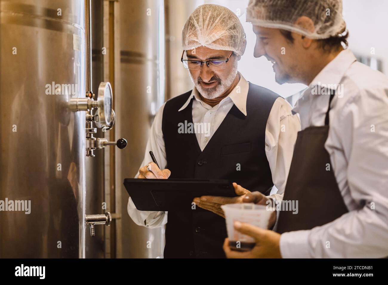 Viticulteur professionnel travaillant dans une grande usine de vinification moderne alcool alcool alcool industrie du contrôle de la qualité et de la fermentation surveillent la couleur vintage à Banque D'Images