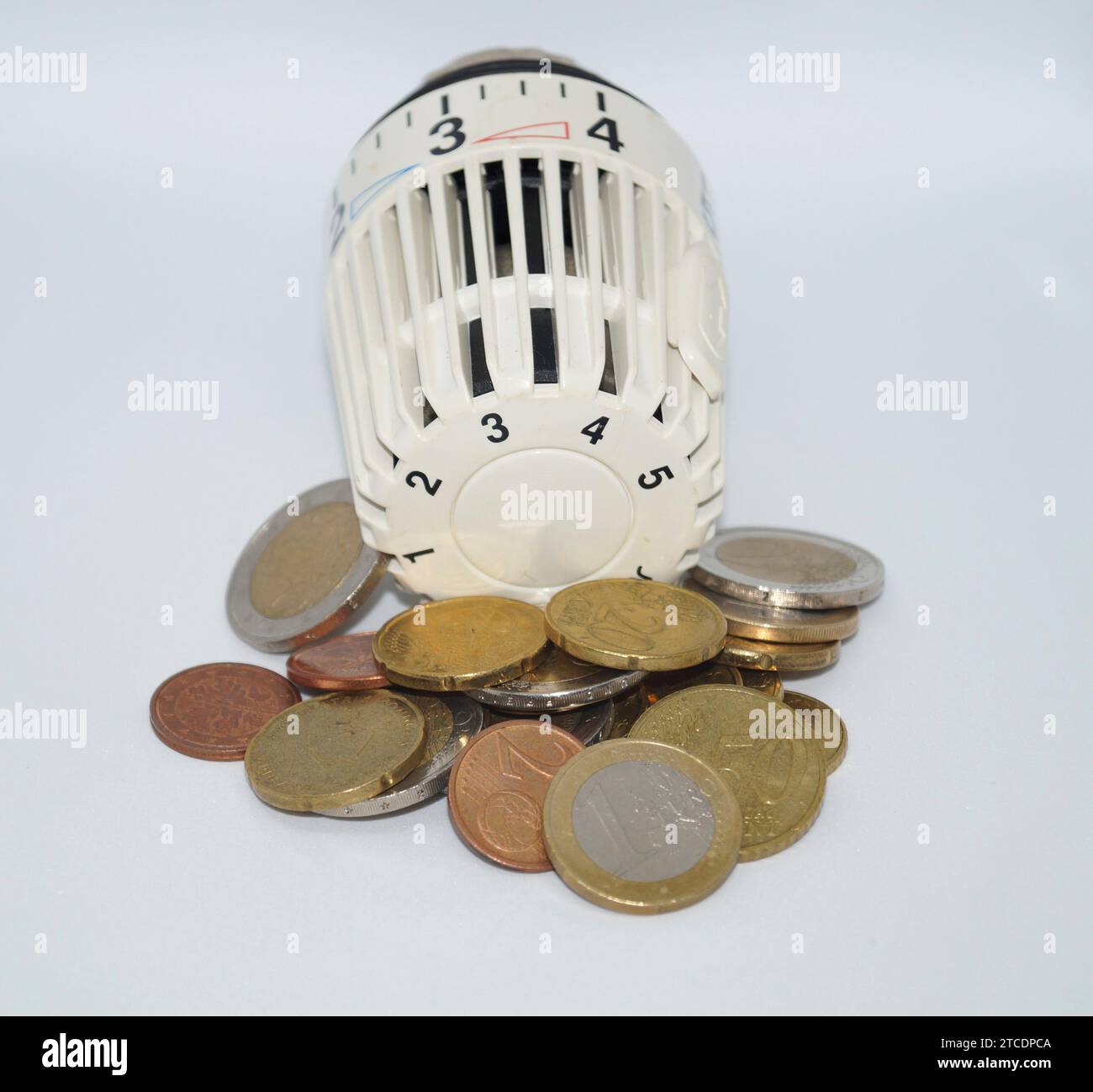 Vanne thermostatique d'un appareil de chauffage avec des pièces en euros, symbole image coûts de chauffage Banque D'Images
