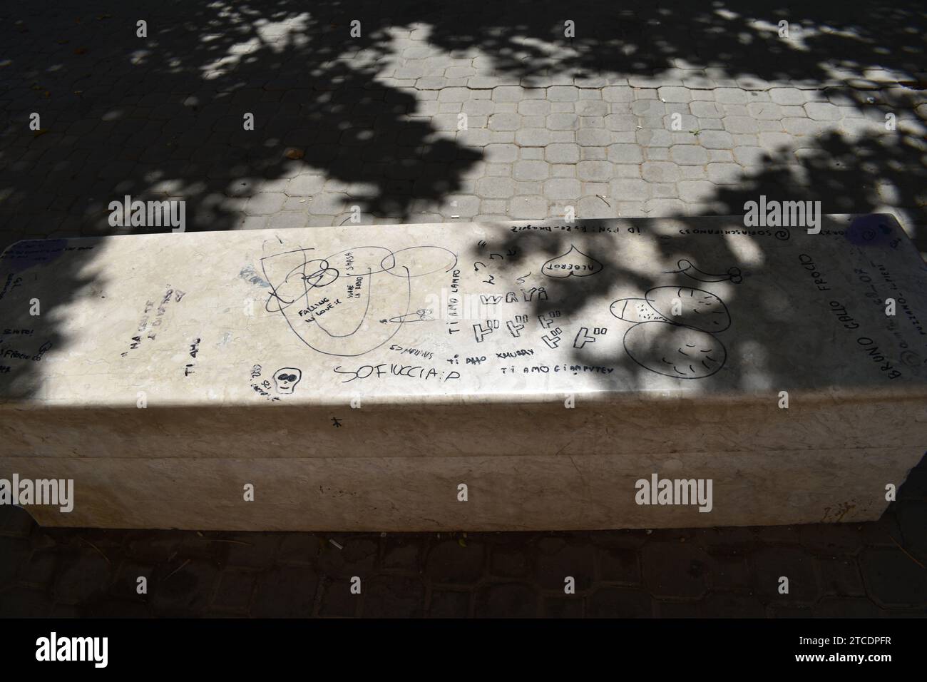 Écritures et dessins italiens au marqueur noir sur un banc en marbre blanc dans le centre historique de Trapani Banque D'Images