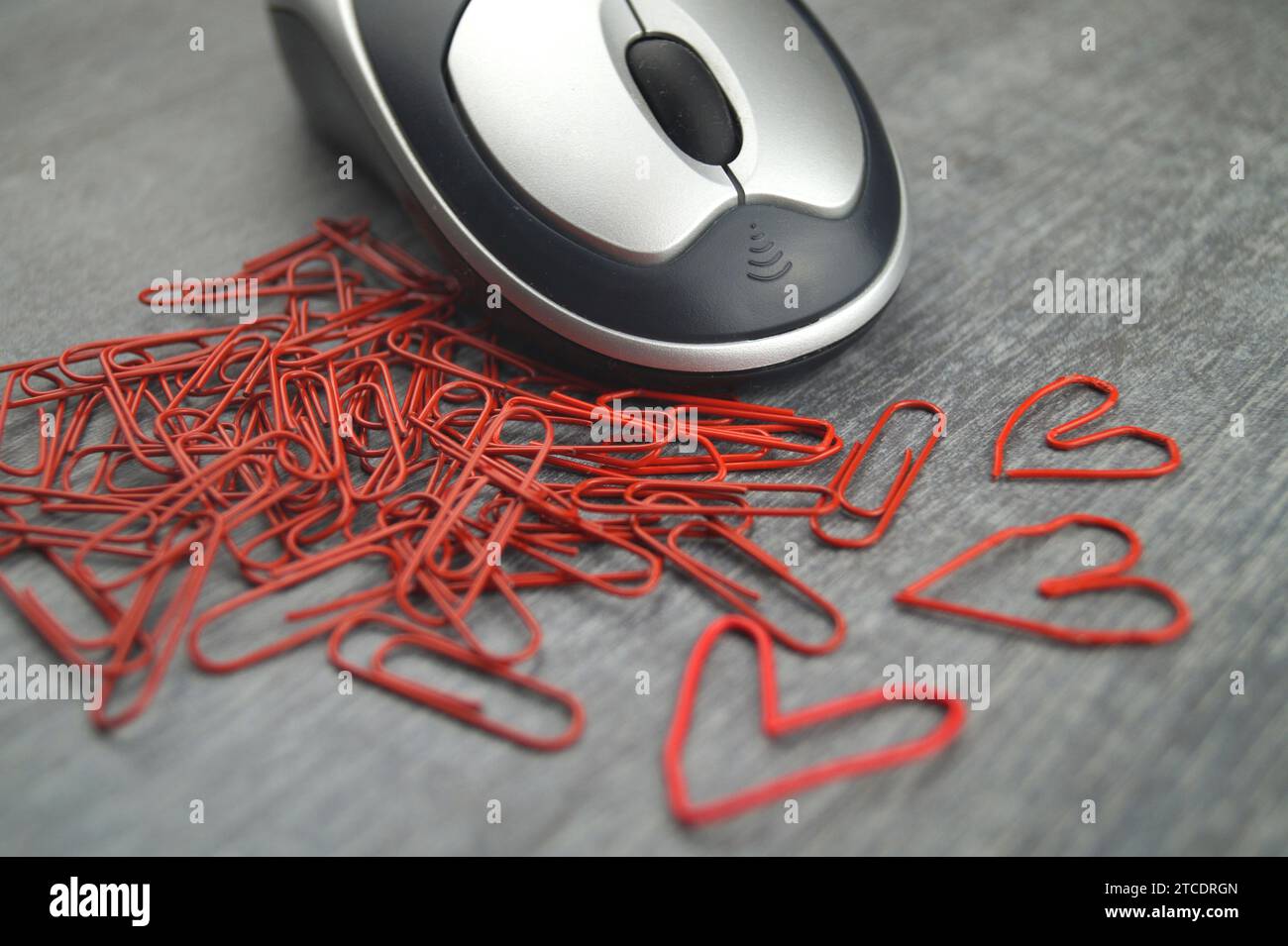 souris d'ordinateur avec trombones rouges, trois d'entre eux en forme de coeur, amour dans le bureau Banque D'Images